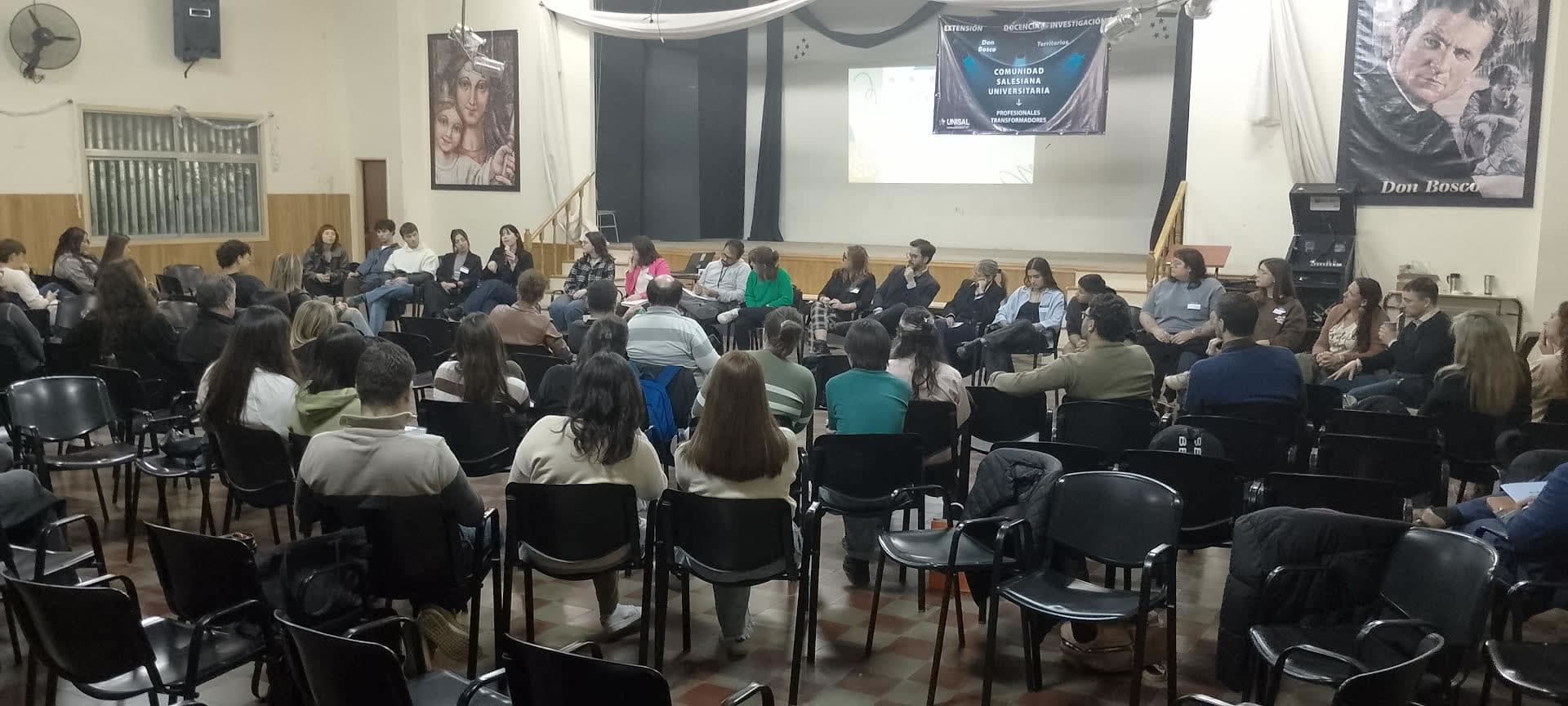 Personas reunidas en una sala con sillas dispuestas para una actividad universitaria.