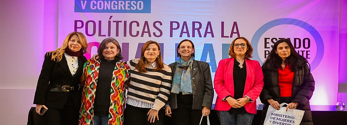 Grupo de asistentes posando frente al escenario de un congreso.